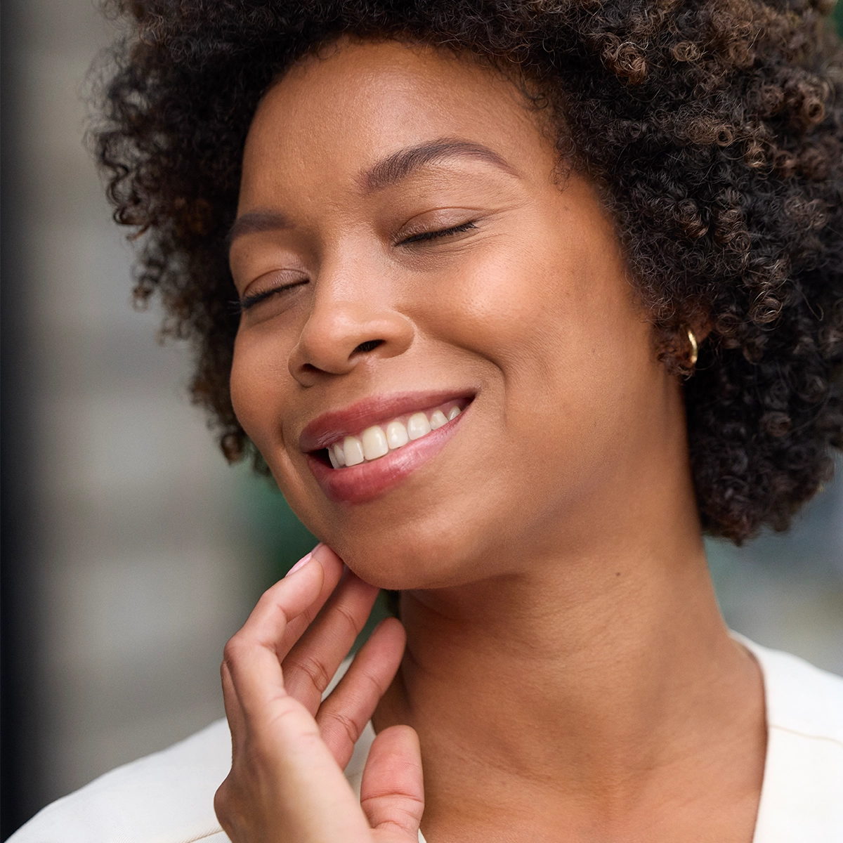 Woman touching her skin and smiling.