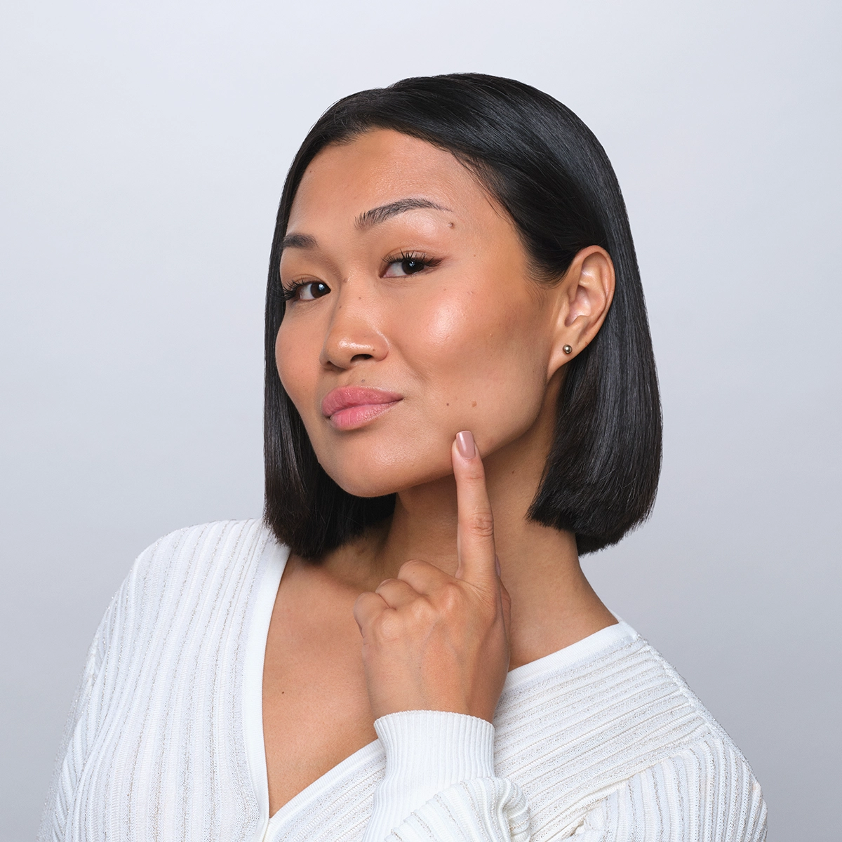Asian woman touching face showing healthy-looking skin.